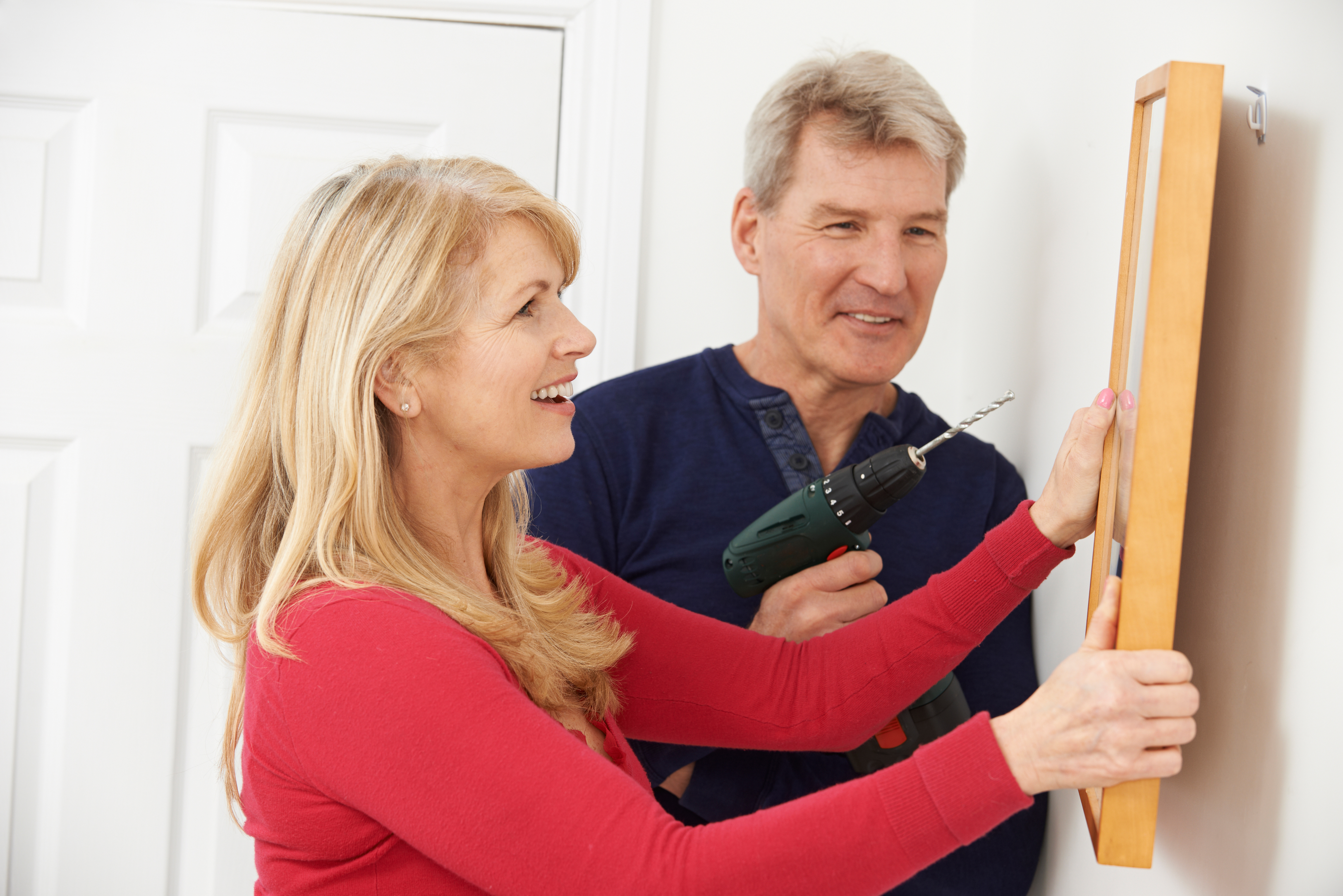 Mature Couple Drilling Wall To Hang Picture Frame
